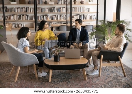 Group of four multinational professionals engaged in collaborative discussion, negotiations or brainstorming gather in cozy coworking office space. Teamwork, problem-solving, or strategy development