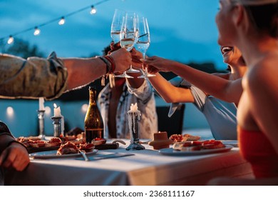 Group of four multiracial friends raising their champagne glasses to do a toast during poolside dinner - Powered by Shutterstock