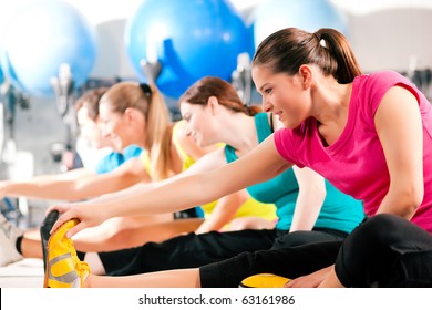 Group of four people in colorful cloths in a gym doing aerobics or warming up with gymnastics and stretching exercises - Powered by Shutterstock