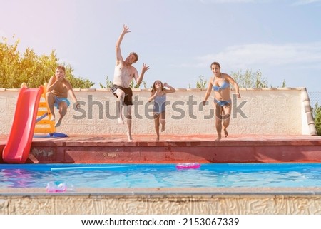 
Group of four people jumping into the pool on a sunny day.