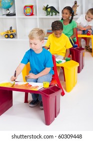 Group Of Four Preschool Kids In Classroom Painting Picture