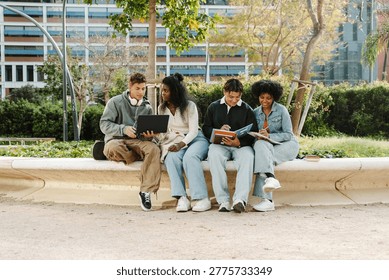 A group of four students sit while two of them write in notebooks and two talk and look at a laptop