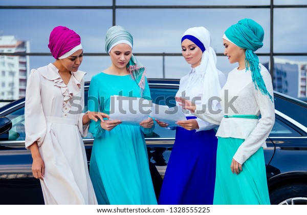 group of\
four successful business multinational Muslims women in stylish\
veiled hijab a turban headscarf is tied up on the head conclude a\
contract for the purchase of a car\
automobile