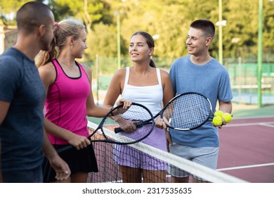 Group of four tennis players standing on court and talking friendly about match - Powered by Shutterstock