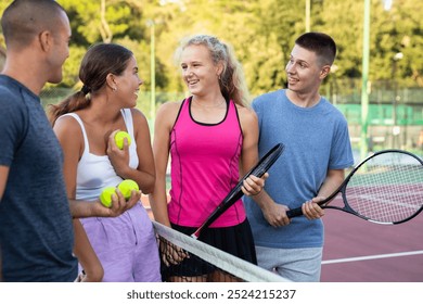 Group of four tennis players standing on court and talking friendly about match - Powered by Shutterstock