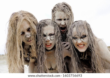 A group of four women are covered with mud 
and dirt.Their hair is tangled in a mess. The facial 
expression shows them to be unattractive and filthy.