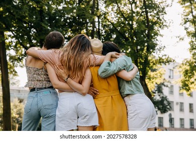 Group of four women outdoors, hugging together from behind.