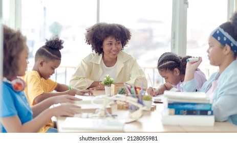 A Group Of Four Young African Students Studying With An African Female Teacher In A Classroom At The School Where Everyone Is Studying Very Hard. This Picture Is An Educational Concept.