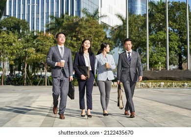 group of four young asian business people walking outdoors on street in modern city - Powered by Shutterstock