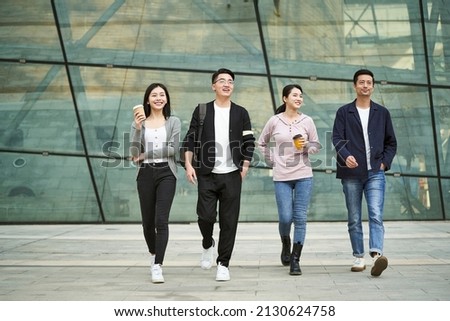 group of four young asian people talking chatting while walking on street in modern city happy and smiling Stock photo © 