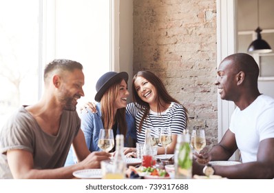 Group Of Four Young People Having Dinner At Restaurant And Talking With Smiling. 