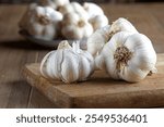 Group of fresh organic garlic bulbs on wooden cutting board. Selective focus. 