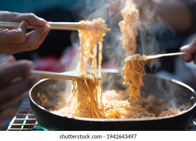 Group Of Friend Enjoy Noodles In Restaurant At Night,Partial View Of People Eating Noodles With Chopsticks.