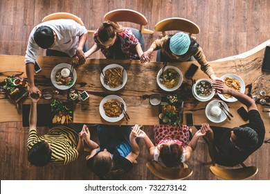 Group of friend pray before having nice food and drinks, enjoying the party and communication, Top view of Family gathering together at home for eating dinner.