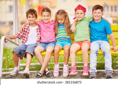 Group Of Friendly Kids Sitting On Bench Outside