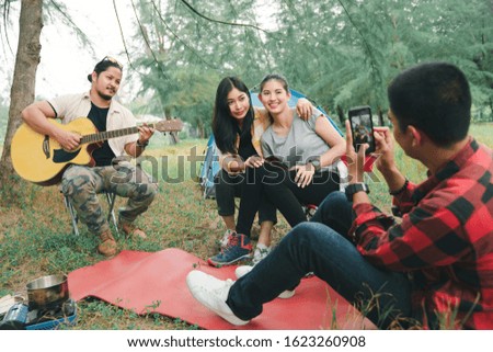 Group of friends asian camp forest adventure and playing guitar together in summer at nature. Asian camping in their tent on the sunny day. Travel in summer holiday concept