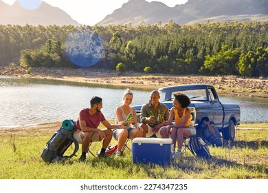 Group Of Friends With Backpacks By Pick Up Truck On Road Trip Drinking Beer From Cooler By Lake - Powered by Shutterstock