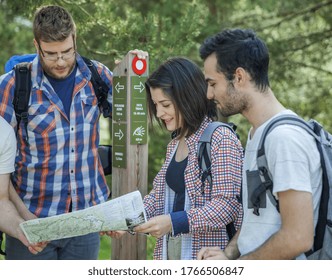 A group of friends with backpacks checking a map in nature