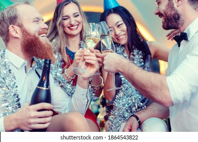 Group of friends in a bar toasting with champagne and celebrating birthday or new years eve