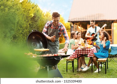 Group of friends at barbecue party outdoors. Young man near grill - Powered by Shutterstock