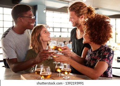 Group Of Friends Beer Tasting Sitting At Bar