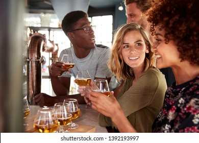 Group Of Friends Beer Tasting Sitting At Bar