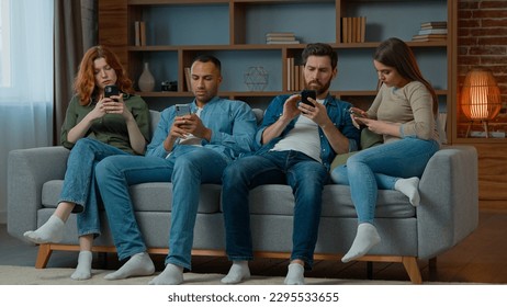 Group friends business people sit on couch with mobile phones chatting in social media ignoring each other multiethnic addicted women and men use diverse devices modern tech addiction gadgets overuse - Powered by Shutterstock