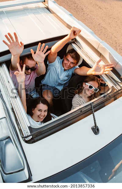 group of friends in car looking up through\
sunroof. road trip.\
friendship