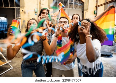 Group of friends celebrate pride with flags and streamers by dancing at a demonstration for support for equality - People having fun together