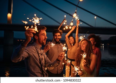 Group of friends celebrating holding sparklers - Powered by Shutterstock