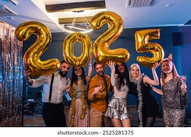 Group of friends celebrating New Years Eve 2025. They hold up gold balloon numbers. - Powered by Shutterstock