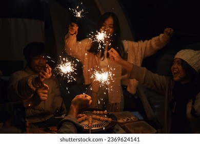 Group of friends celebrating together with a sparkling fireworks in the evening.