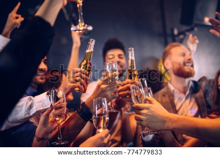 Group of friends cheering with champagne and beer
