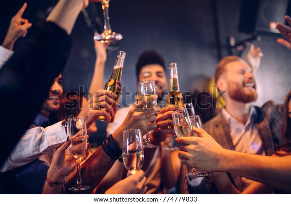 Group of\
friends cheering with champagne and\
beer