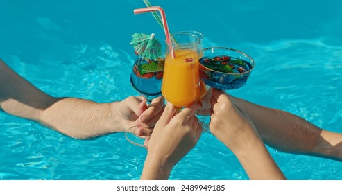 Group of friends clinking glasses with cocktails against the backdrop of a swimming pool - Powered by Shutterstock