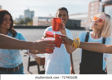 group of friends clinking glasses on alcohol on roof party