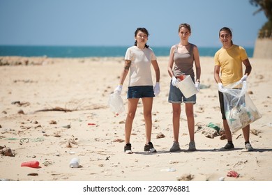 Group Of Friends Collecting Garbage On Beach Cleanup Day