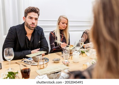 Group Of Friends Conversating During Dinner. Handsome Man Talking And Eating Sushi With Female Friends At A Private Dinner Party. 