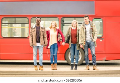 Group Of Friends Crossing The Road With Traditional Red Bus Behind - Autumn Or Winter Concept Of Social Life With Young People Hanging Out Together - Neutral Color Tones With Focus On Guys And Girls