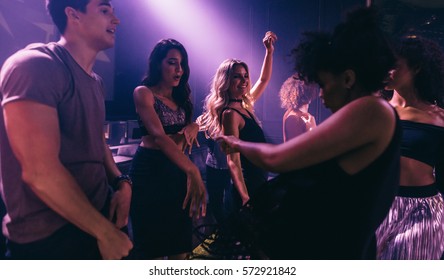 Group Of Friends Dancing In Club. Young Men And Women Having Fun At Disco  Nightclub.