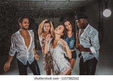 Group of friends dancing under the rain - Multiethnic people having party