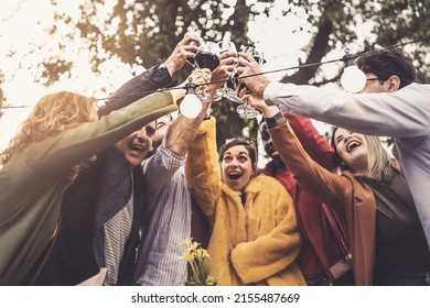 A group of friends of different ethnic backgrounds meet at sunset in the countryside to toast together on the terrace of the farmhouse restaurant - people drinking lifestyle concept - vintage filter - Shutterstock ID 2155487669