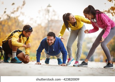 Group of friends doing push-ups at the park and making fun,smiling and laughing.Autumn season. - Powered by Shutterstock