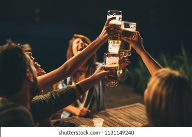 Group of friends drink beer on the terrace and toast during summer night - Shutterstock ID 1131149240
