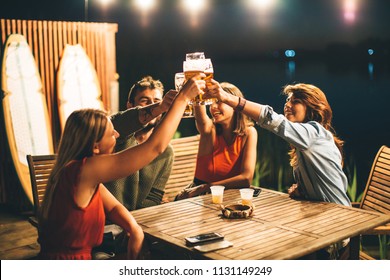 Group Of Friends Drink Beer On The Terrace And Toast During Summer Night