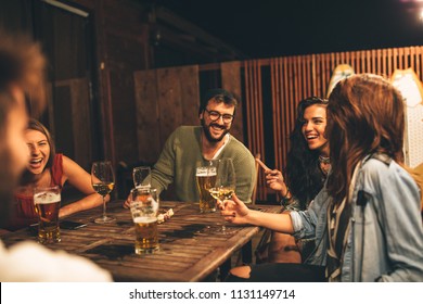 Group Of Friends Drink Beer On The Terrace During Summer Night