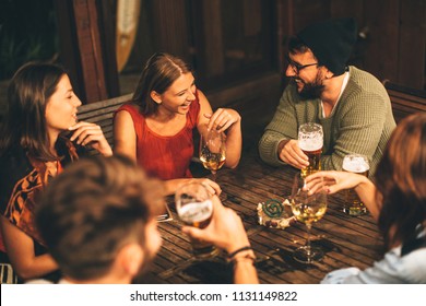 Group Of Friends Drink Beer On The Terrace During Summer Night