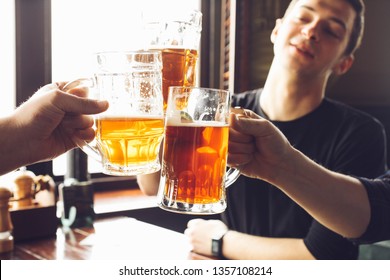 Group of friends drinking beer from mugs in brewery pub in afternoon. Concept alcohol.