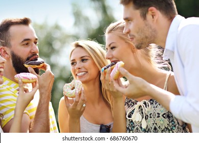 Group Of Friends Eating Donuts Outdoors