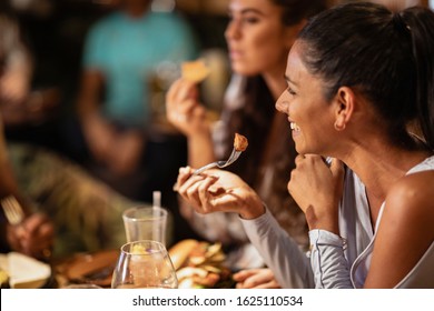 A group of friends eating a meal at a reestaurant. The main focus is a Sri Lankan woman eating.